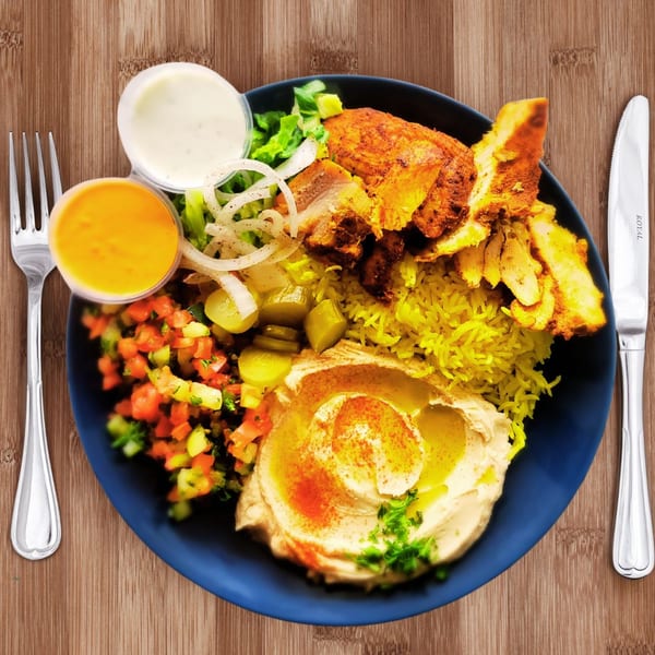 ZamZamz Mediterranean Grill's chicken shawarma plate with rice, hummus, salad, and sauces on a blue plate.