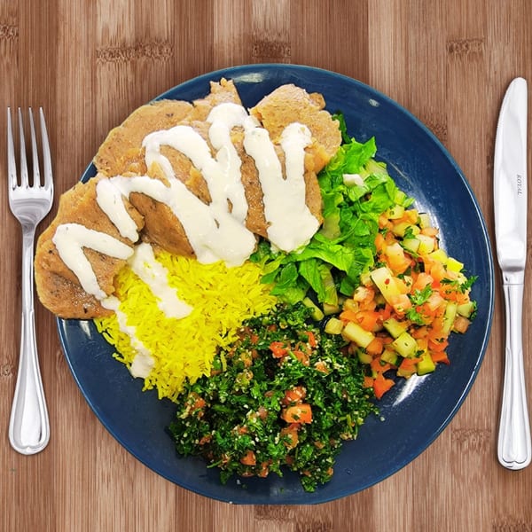 A Mediterranean platter with gyro meat, yellow rice, tabbouleh, salad, and white sauce on a blue plate.